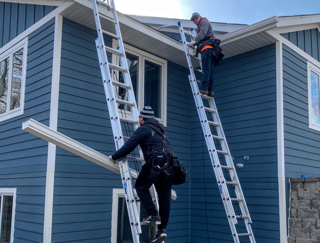 contractor installing replacement gutter on ladder